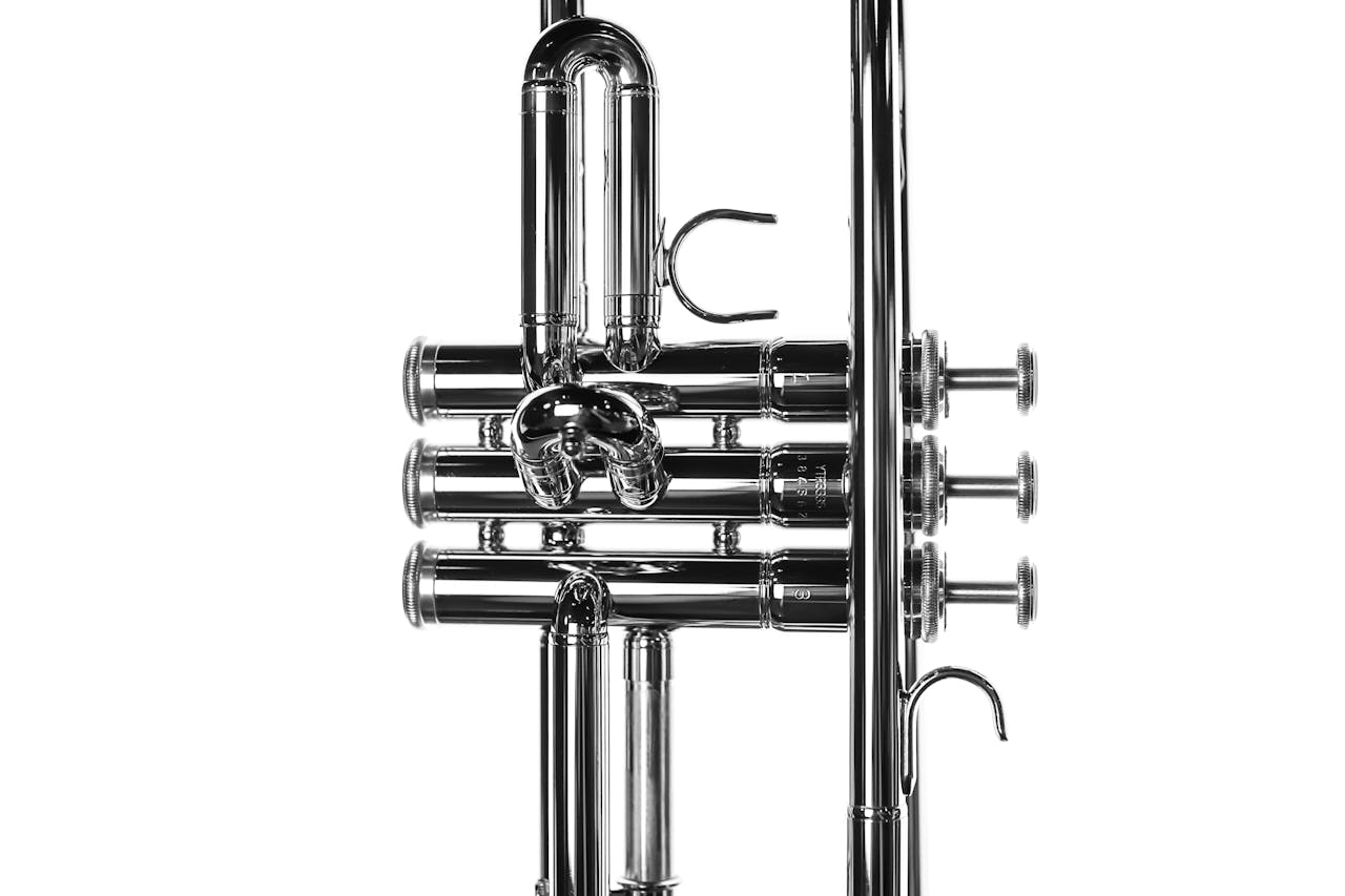 services-03 Detailed close-up of a silver trumpet showcasing valves and tuning slides against a white background.