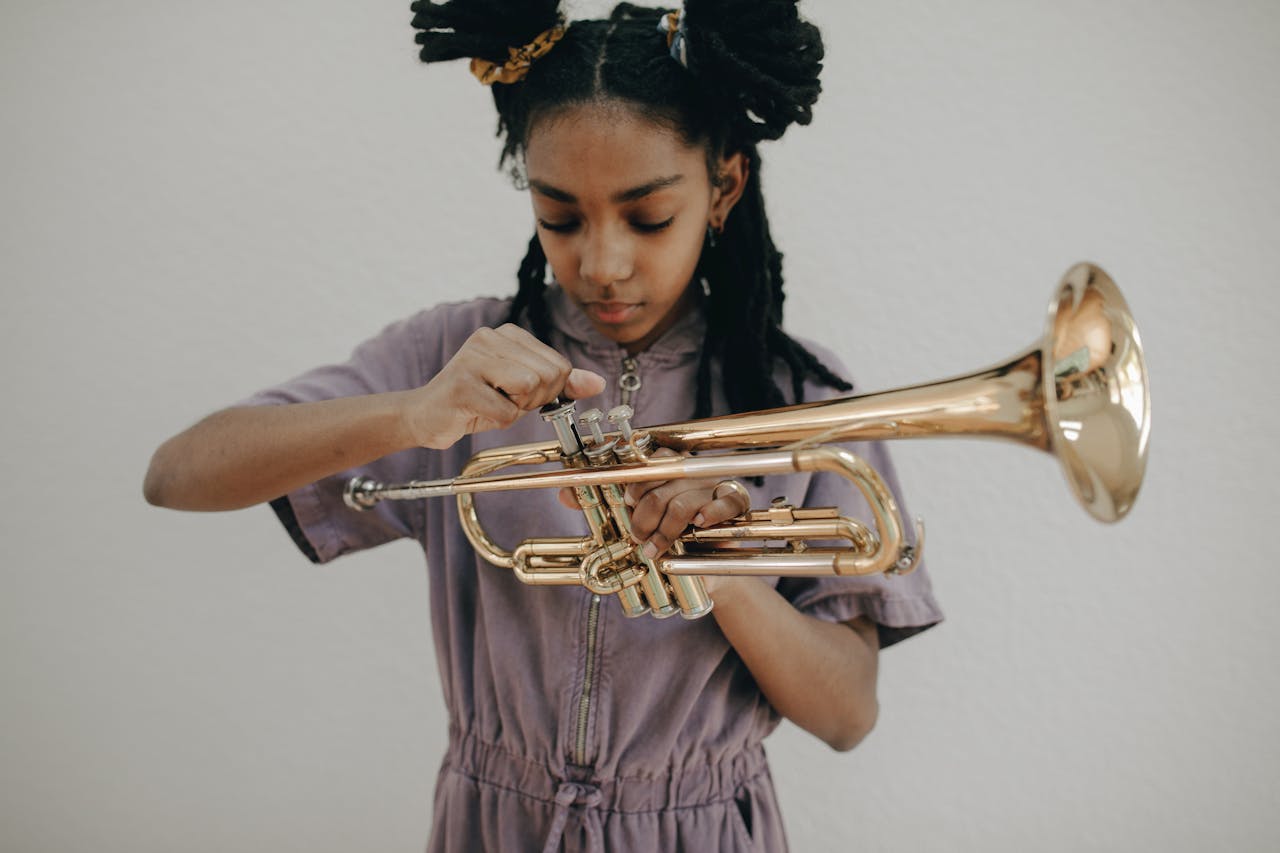 hero-img-02 A young girl focuses on playing a brass trumpet during a studio photoshoot. Perfect for music-related themes.