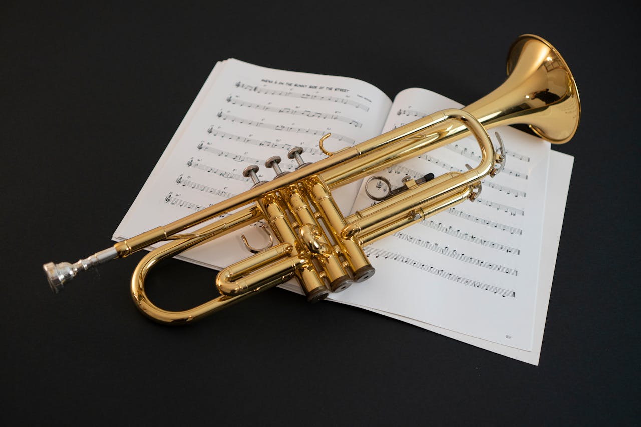 about-01 Golden trumpet resting on open sheet music, featuring melodic notes. Perfect for jazz and classical music themes.